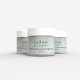 Three jars of 'Tallow Me Pretty Anti-Aging Cloud Cream' are arranged in a staggered line, showcasing the smooth, sage-green cream against the crisp white of the labels and lids. The simple, elegant font on the jars spells out the brand and product name, suggesting a luxurious skincare experience. The jars' glassy surface reflects light softly, adding to the clean and serene aesthetic of the product design.