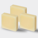 Three large, creamy white bars of tallow soap are stacked closely together, their smooth surfaces glowing with a gentle sheen, reminiscent of pure and natural skincare products.